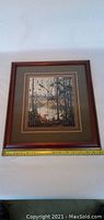 Framed print of a forested lake scene with a wooden frame and double matting.
