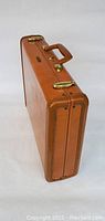 Side view of tan Samsonite leather briefcase showing brass hardware and handle
