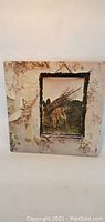 Front cover of Led Zeppelin IV album showing weathered wall and man carrying sticks artwork