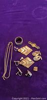 Top-down photo of assorted silver jewelry pieces on purple cloth background.