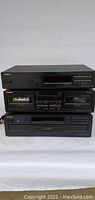 Front view of the three Onkyo components stacked: the FM Stereo AM Tuner T-4040 at the top, the stereo cassette tape deck TA-RW144 in the middle, and the compact disk changer DX-C140 at the bottom. All devices have a black finish with display windows and control buttons visible.
