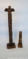 Pair of two wooden totem poles, large with eagle figure and small with missing wings