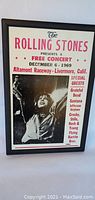 Full view of framed Rolling Stones free concert print from 1969 with black and white photo of band member, and red and black text.
