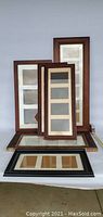 Six photo frames grouped together showing two matched vertical four-photo frames in front, other frames behind