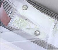 Close up of clear shower curtain liner showing transparent PEVA material and 2 silver metal grommets for hanging.