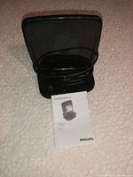Black Philips HD TV indoor antenna with base, folded antenna panel on top, and USB cable coiled around base alongside a folded user manual with product image on front.