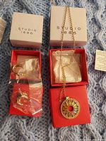 Photo showing necklace with circular pendant and matching earrings inside Studio 1886 boxes.
