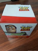 White rectangular box with Toy Story logo and Buzz Lightyear illustration, showing product name and details on front and top.