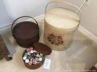 Image showing the large painted wooden bucket with floral design and smaller round wooden box with thread spools inside, both with lids.