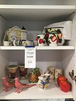 Shelf with assorted decorative ceramic salt and pepper shakers, napkin holders, and pink bird figurines