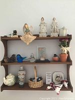 Photo of wooden wall shelf with assorted ceramic, glass, porcelain figurines and decor items arranged on it.
