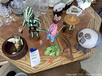 View of assorted wood carved figurines on round wooden table from overhead angle.