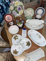 Full view of entire porcelain collection on table showing plates, bowls, divided dish, floral vase, and fruit ornament