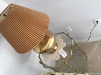 Brass table lamp on octagonal shaped brass framed glass top end table, with plugs and power cord visible