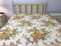 Full view of the assembled queen size bed with floral mattress and cream colored wooden headboard.