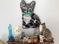 Wide view showing cat wall hanging, large ceramic cat figurine, white Persian cat figurine, assorted glass pieces, and TY Beanie Animals.