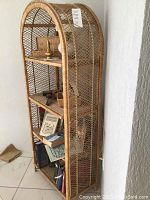 Side-angle view of the natural wicker shelf unit showing four shelves, arched top, and lattice woven sides and back.