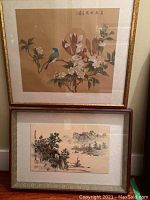 Two framed Asian prints, one of a blue bird on a flowering branch, the other a landscape with mountains and water.
