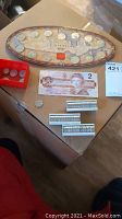 Overview of lot showing wooden oval Canadian coin set, Canadian $2 bill, three coin rolls and loose coins on cardboard box.