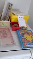 Overview of the lot showing the yellow box for international coins, wooden stamp holder, several paper banknotes, and Pokemon notebook.