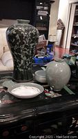 Group photo of all ceramic items on table including tall black and white floral vase, shorter white vase, bowls, sauce dish and ceramic ducks