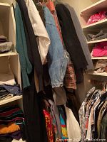 Closet corner with multiple jackets, coats, sweaters hanging and folded on shelves