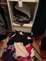 Pile of assorted women's tops including black, cream, dark purple, and patterned items.