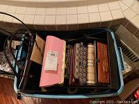Top down view of various wallets and small purses inside a blue plastic bin, showing a mix of textures including crocodile embossing and fabric patterns