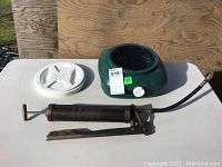 Full view of the Blitz oil drain tank, white lid, and black grease gun tool