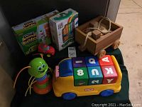 Full view of all toys including Little Tikes bus with blocks, wooden block wagon, caterpillar toy, red car, Lakeshore Animal Builders box, and Eric Carle books set.