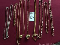 Seven gold tone necklaces with three pendants laid out on burgundy fabric