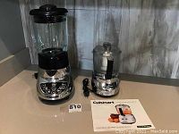 Cuisinart food processor with clear container and power cord, manual in front