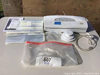 Full lot overview including vacuum sealer unit, sealing rolls, vacuum bags, vacuum hose, and accessories on white table.