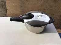 Side view of stainless steel pressure cooker showing the main body, lid, and handle