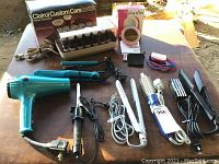 Full view of hair styling devices including Clairol Custom Care curler set, two flat irons, curling irons, hair dryer, and assorted hair tools.