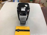 Front view of the black Keurig K-Cup brewing system on a table with original yellow welcome guide booklet.