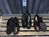 Three pairs of ladies shoes displayed including one pair of Romika black loafers with pewter accent, Franko Sarto brown leather shoes, and J.Pilner black slip-ons with zipper.