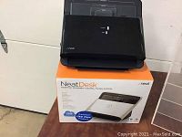 Photo of the NeatDesk desktop scanner on top of its box, showing its black device and packaging.