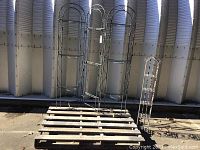 Photo showing three hinged metal panels and smaller decorative plant holder all placed on wooden pallet outdoors.