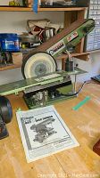 Front view of the Central Machinery belt and disc sander placed on a wooden bench with the manual in front.