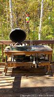 Front view of Big Green Egg on wooden cart on deck with accessories