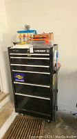 Full front view of black steel Husky tool chest showing drawers, decals and caster wheels