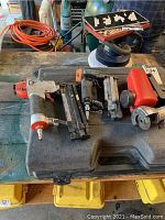 Overview of six pneumatic tools laid across a black carrying case on a workbench