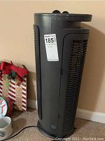 Side view of tall black vertical Holmes heater showing power cord and MaxSold tag.