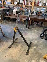 Full view of the black metal adjustable roller stand with padded roller top in a garage setting