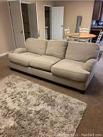 Full front view of the grey 3-cushion sofa in a living area on carpet, showing its length and cushion fit.