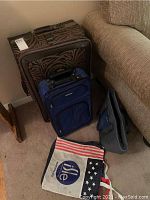 Full view of two suitcases and three soft tote bags arranged on carpet near couch