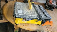 Front perspective of QEP 650XT electric tile wet saw with manual cutter showing the main cutting table, blade guard, and manual cutter handle in dusty condition.