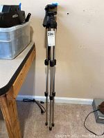 Full view of the tripod standing upright showing three extendable metal legs and rubber feet.