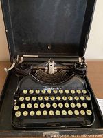 Top-down view of open typewriter in case showing keyboard and mechanism